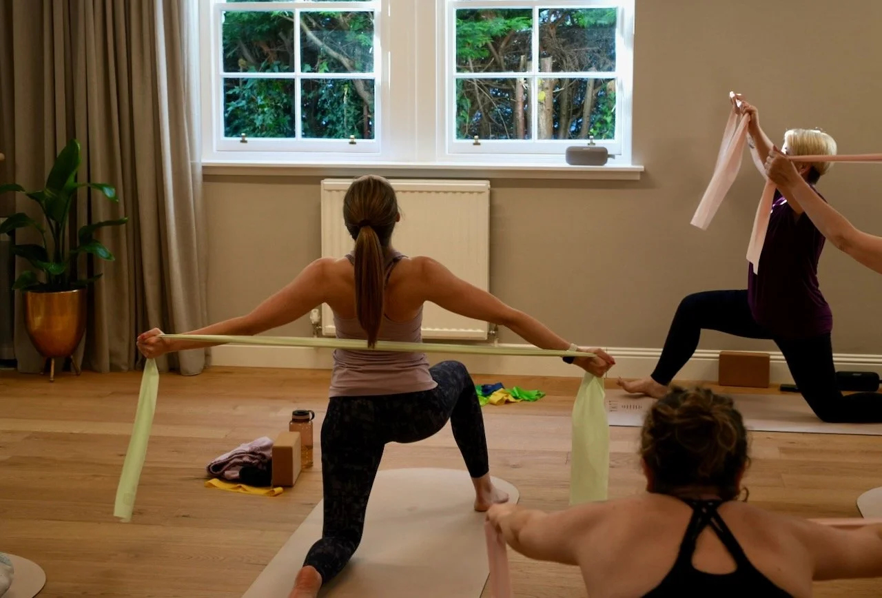 Kat Aydin cueing clients through a strap-supported lunge during a Yoga class at Luma Pilates Edinburgh