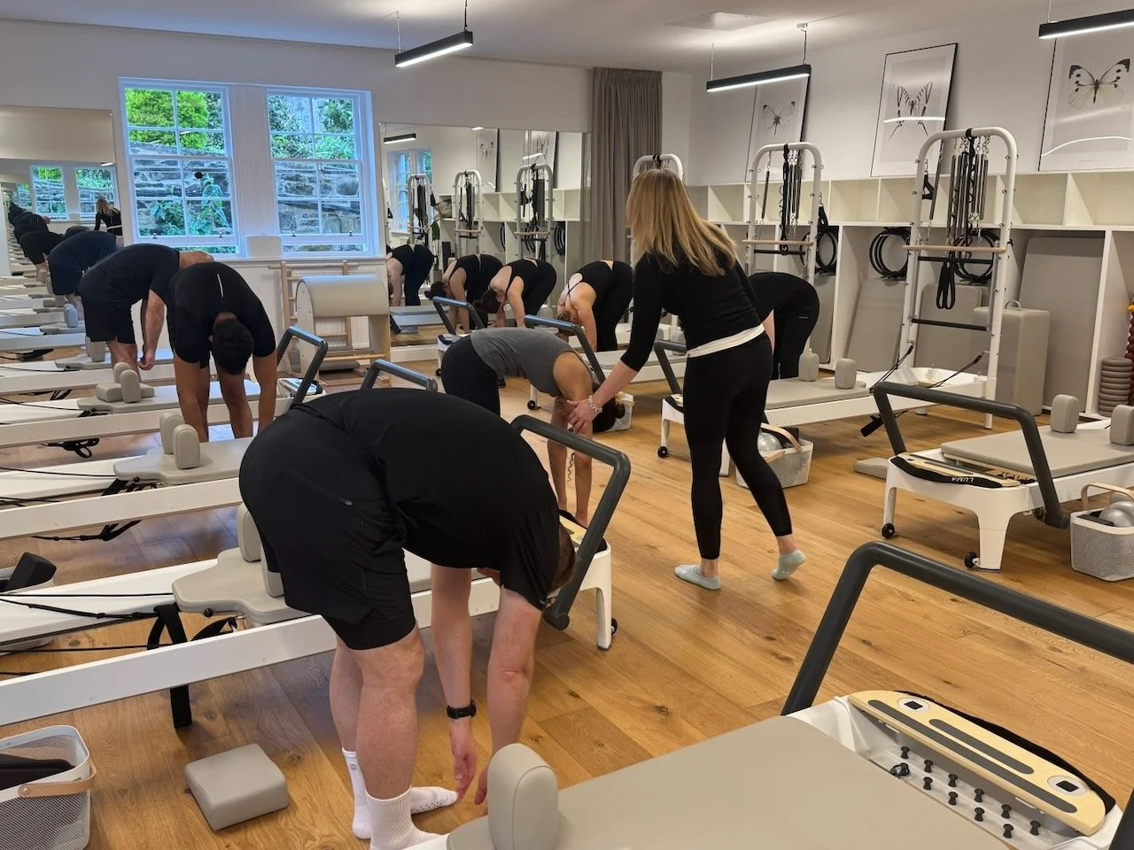 Lucia Poulter guiding clients during a standing roll-down at their Reformers at the end of a class at Luma Pilates in Edinburgh