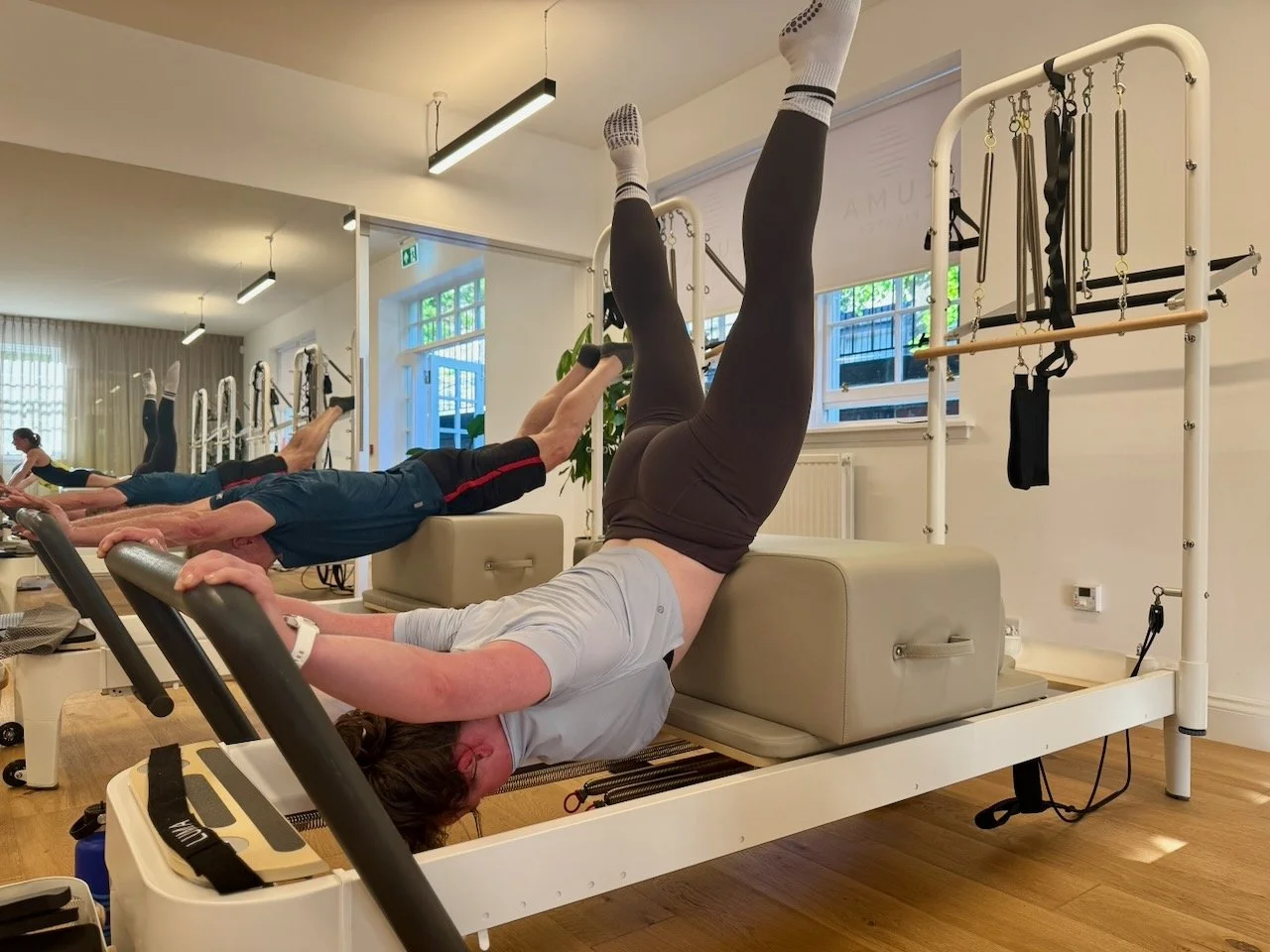 Emma performing the Swan Dive exercise on a Reformer during a Reformer Pilates 3 class at Luma Pilates Edinburgh