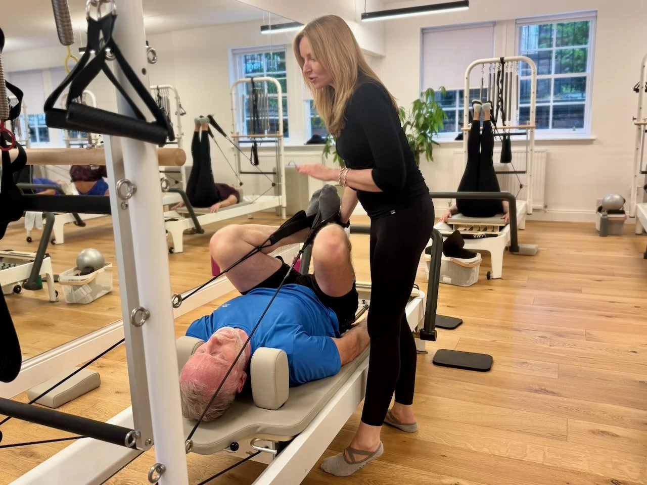 Lucia Poulter guiding a client's leg position during a Reformer Pilates class at Luma Pilates, Edinburgh