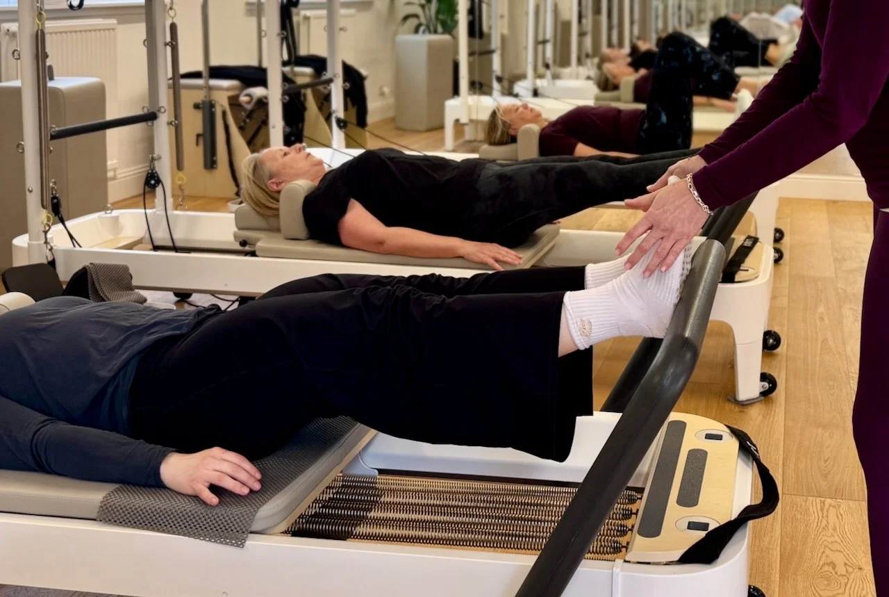 Lucia adjusting a client's foot position during a Reformer Pilates class at Luma Pilates, Edinburgh