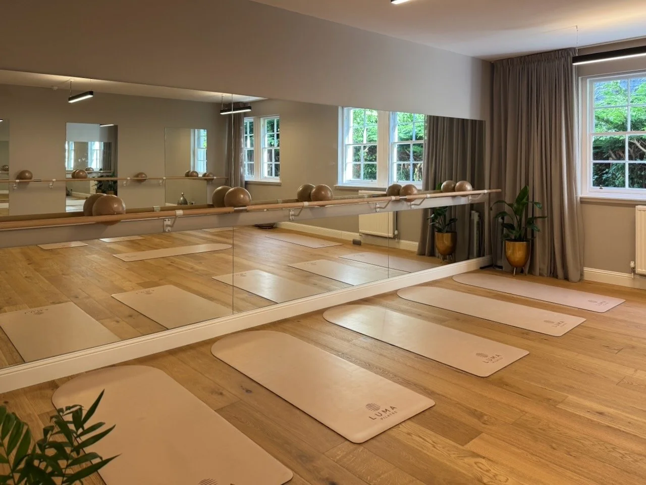 Luma Pilates Studio B in Edinburgh's New Town showing Luma branded mats laid out on oak floors with barre, large windows and natural light