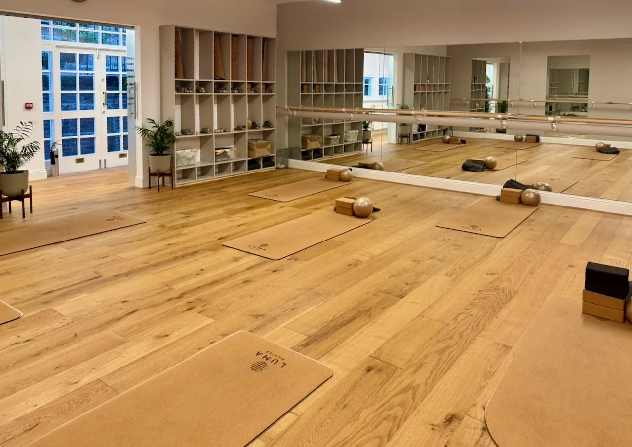 Studio B at Luma Pilates Edinburgh. Cork mats laid out for a Mat Pilates class, barre and mirror wall