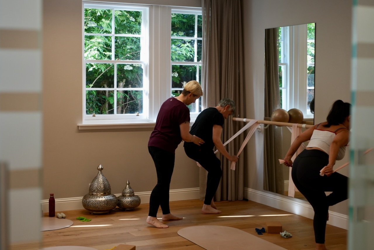 Kat Aydin cueing a client using a strap at the barre in Studio B at Luma Pilates Edinburgh