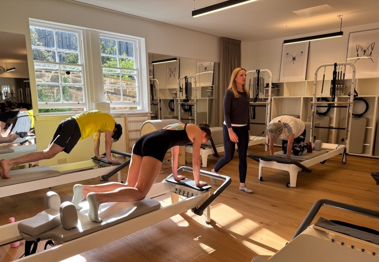 Clients performing intermediate Reformer exercises during a Reformer Pilates 2 class at Luma Pilates Edinburgh with Lucia cueing