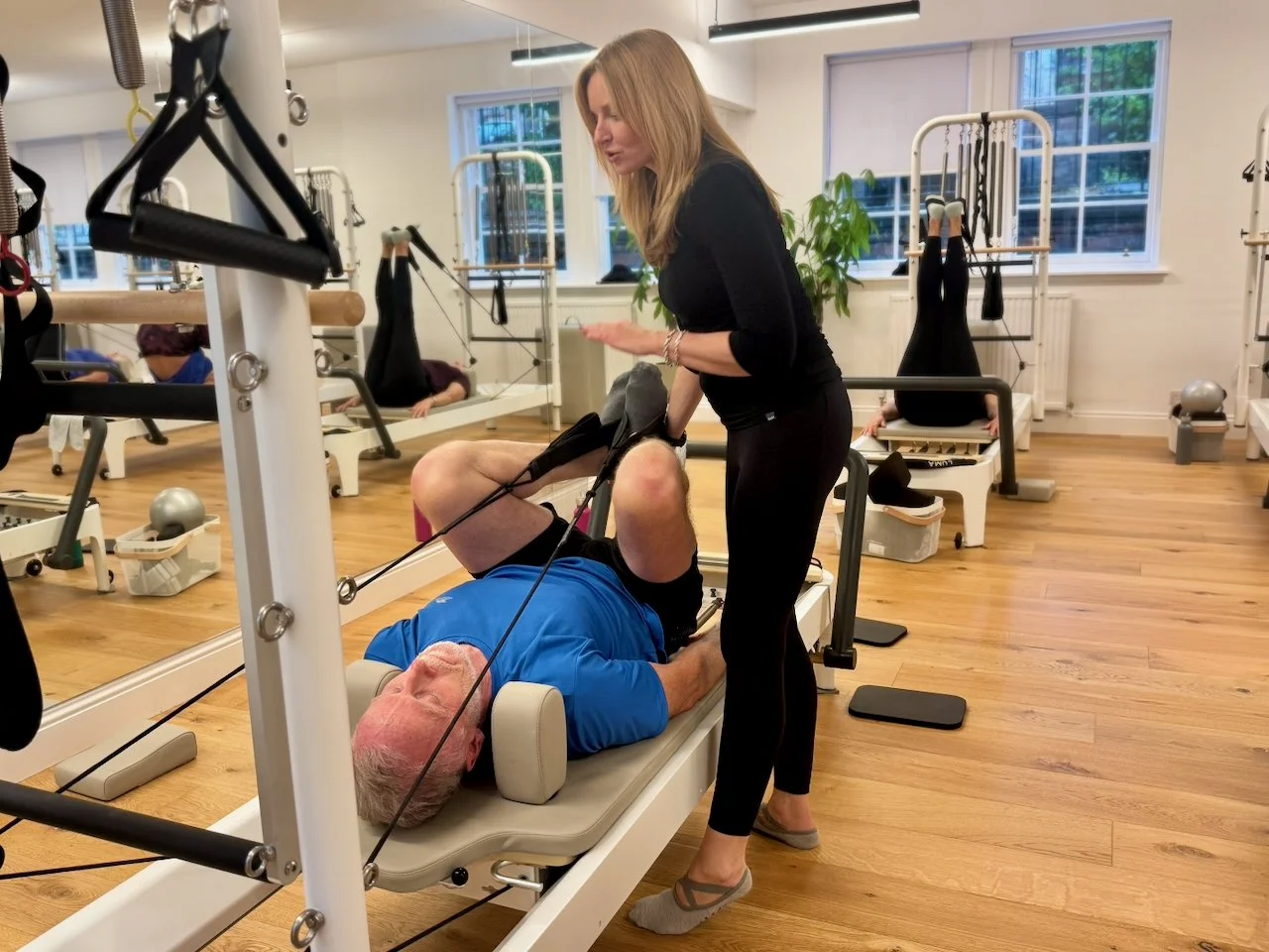 Lucia Poulter making a hands-on adjustment to a client on the Reformer at Luma Pilates Edinburgh