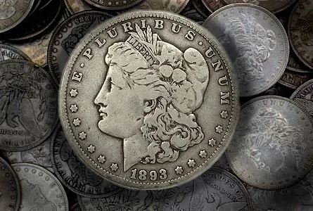 Close-up of a silver Morgan silver dollar coin from 1893 among other coins.