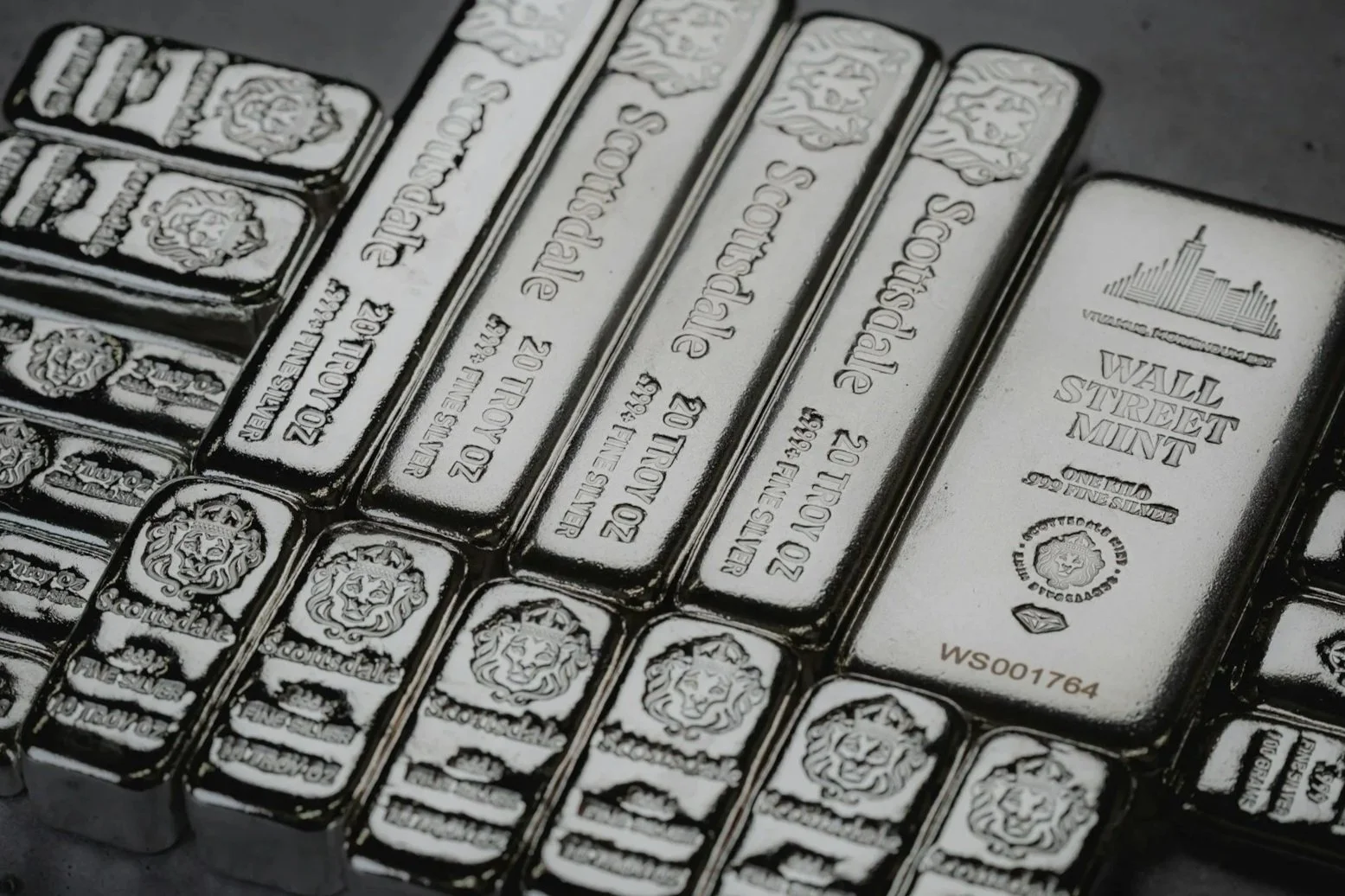 A collection of silver bars with engravings and markings, including 'Wall Street Mint,' indicating they are silver bullion bars.
