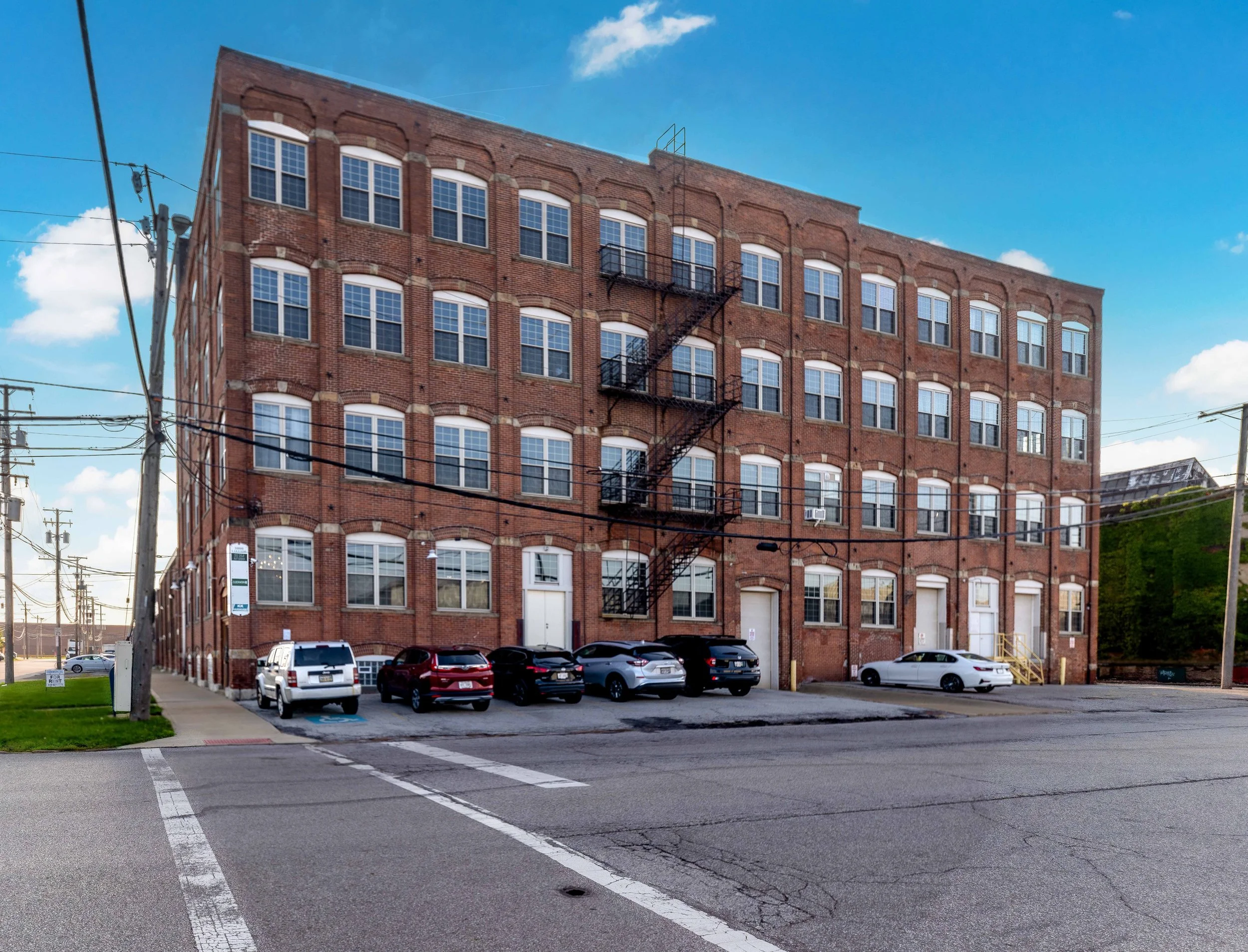 A large, multi-story brick building with multiple windows and an external fire escape on the front.