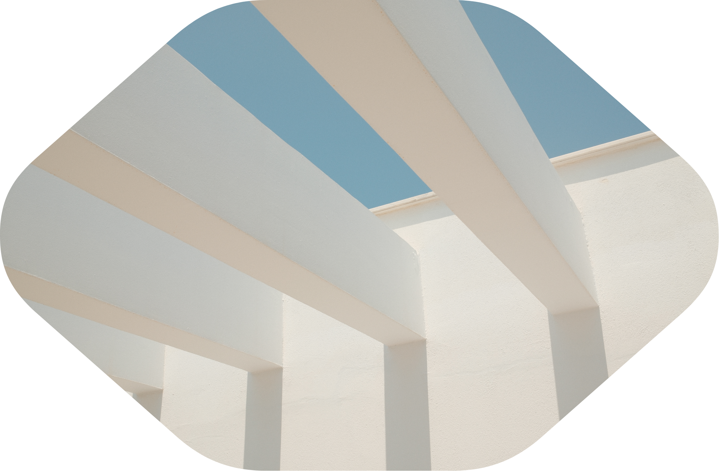 Low-angle view of white modern architectural structure with flat roofing and blue sky background.