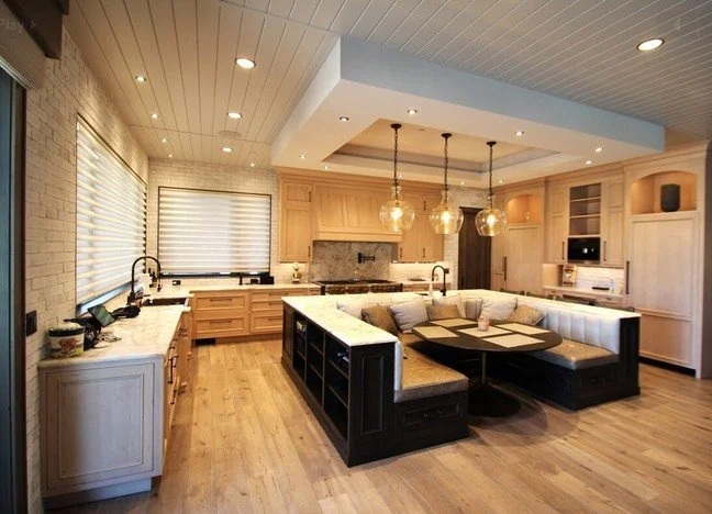 Modern kitchen with light wood cabinets, a black and white island, and pendant lighting over the seating area.