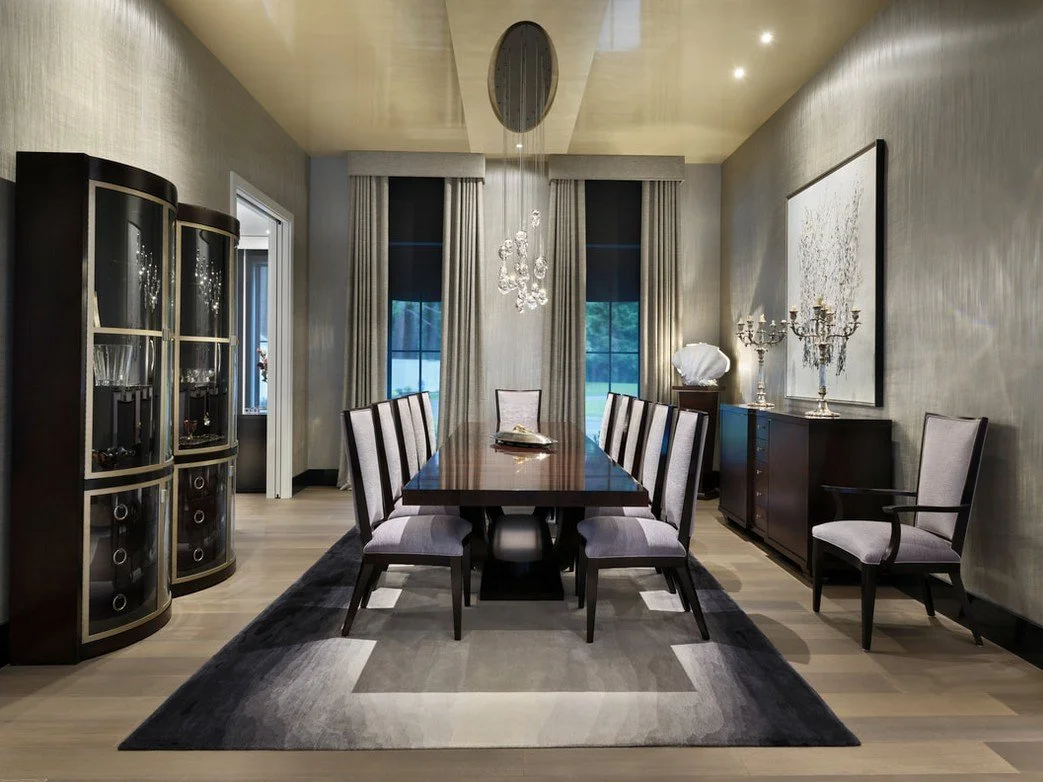 Elegant dining room with a long wooden table, upholstered chairs, a chandelier, and decorative art on the walls.