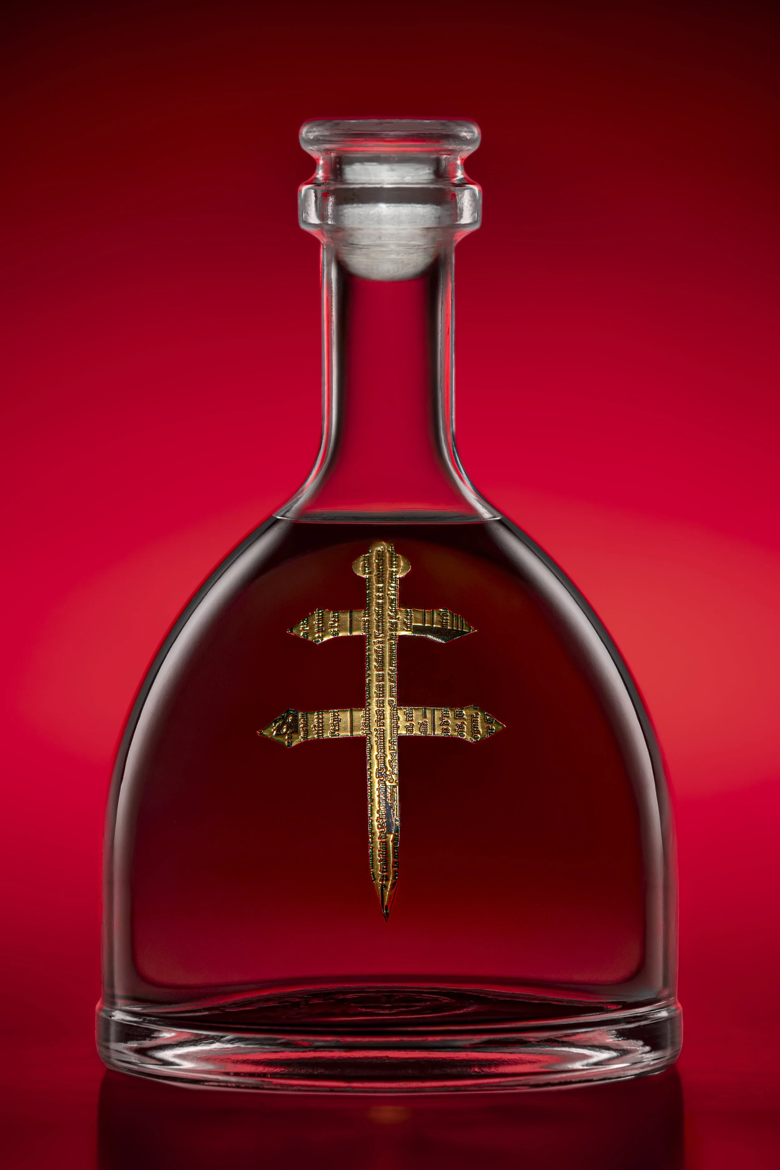 A glass bottle with a gold-colored currency symbol inside, set against a red background.
