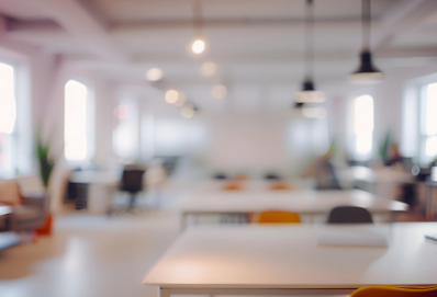 Empty office space with desks, chairs, and hanging lights, blurred background.