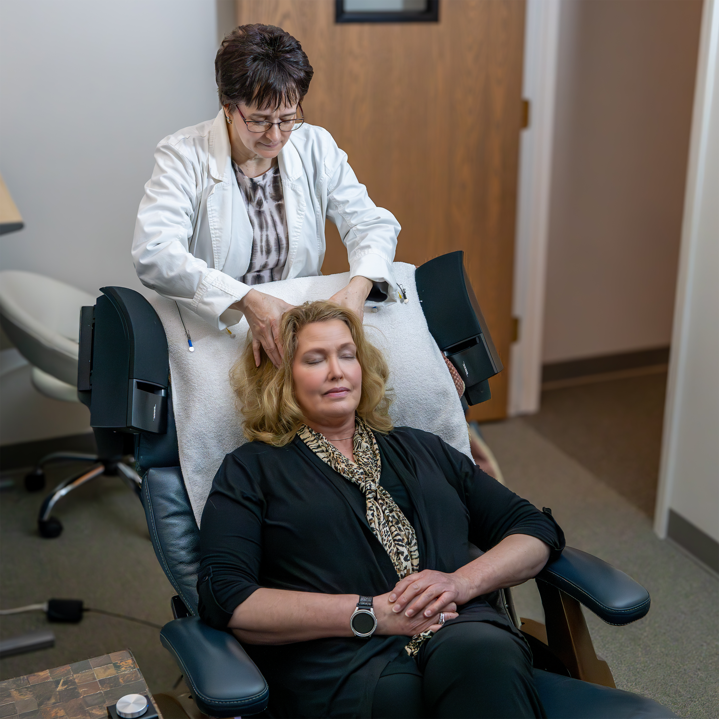 A woman is having EEG sensors placed on her head before she begins her audiovisual mirror, neurofeedback therapy