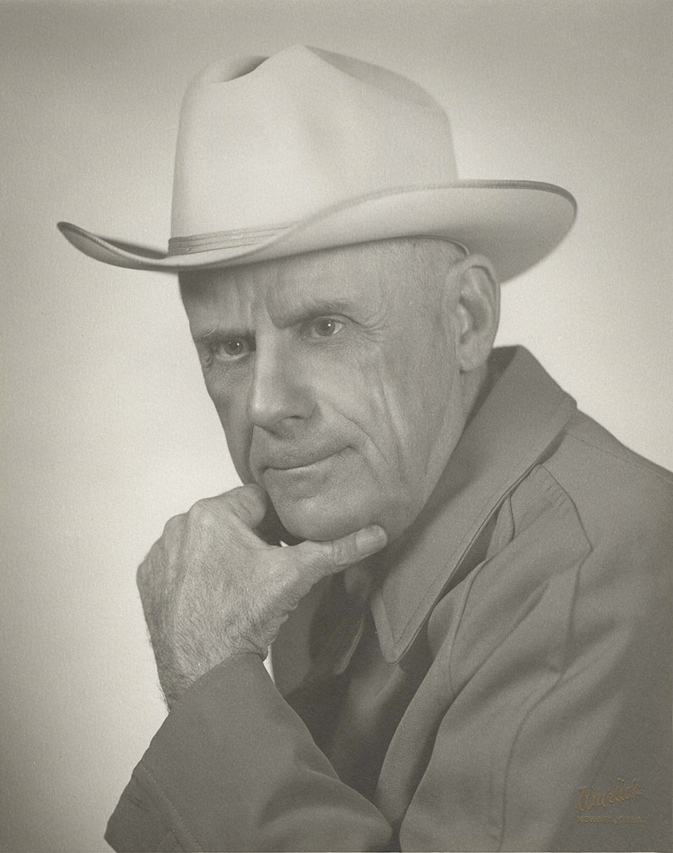 A black-and-white portrait of an elderly man wearing a cowboy hat, with a thoughtful expression, hand resting on his chin, and wearing a jacket.