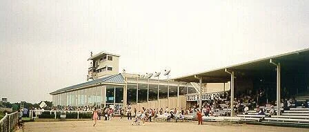 Vintage photo of a 1960s outdoor stadium or pavilion with a large glass-fronted building and a tower in the background.