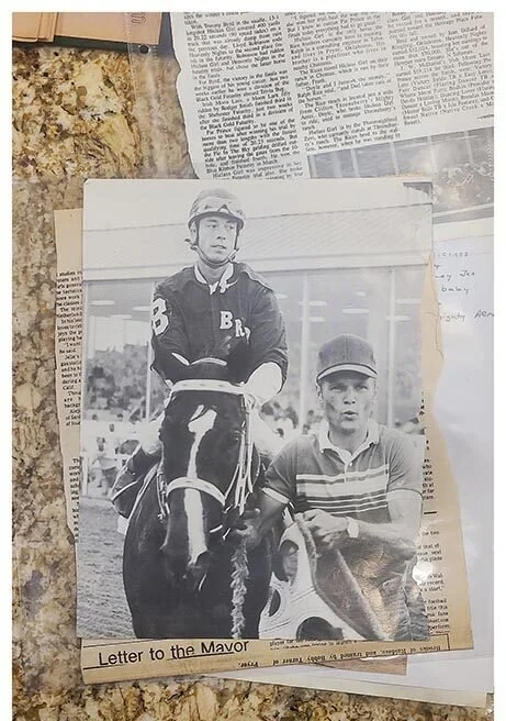 Black and white photo of a jockey riding a horse and a young man holding a fish, labeled "Letter to the Mayor."