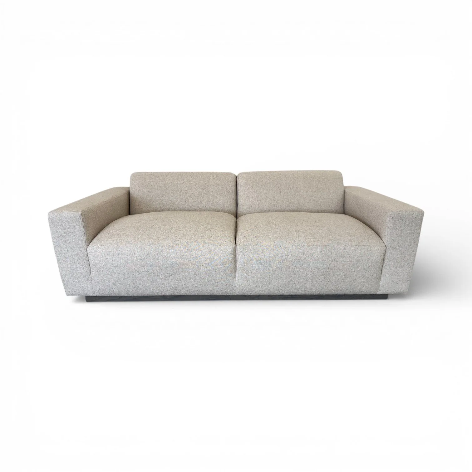 A light beige fabric sofa with wide armrests and a cushioned back, set against a plain white background.