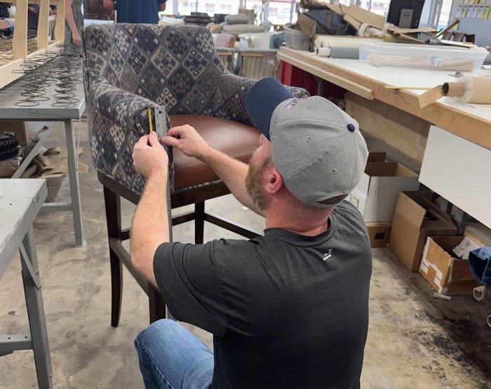 Thayer Upholstery craftsman reupholstering a chair in workshop using professional tools