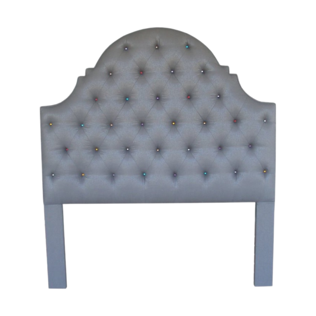 A headboard with a semi-circular top and blue upholstery, decorated with colorful buttons arranged in a diamond pattern.