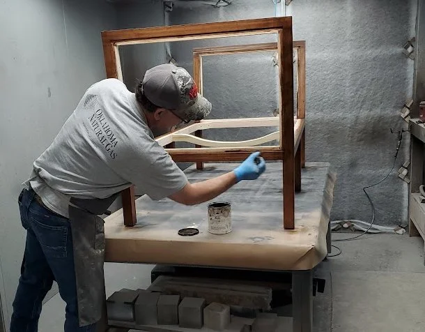 craftsman refinishing a wooden chair frame with stain in workshop
