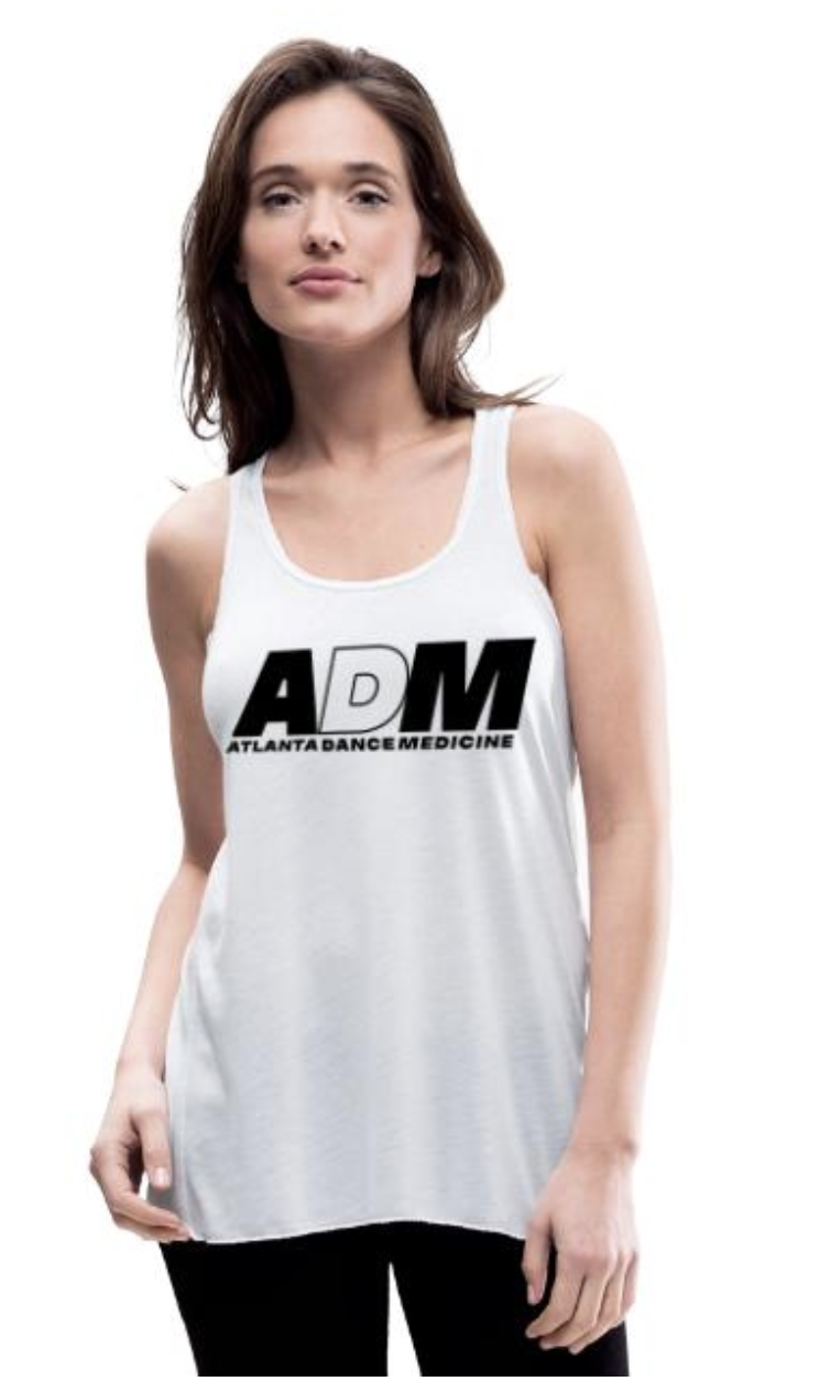 A young woman with shoulder-length brown hair wearing a white tank top with the logo 'ADM' and the text 'Atlanta Dance Medicine' printed on it, standing against a white background.