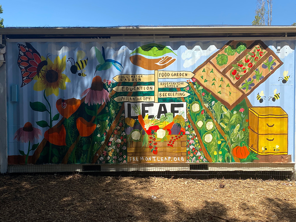 Colorful mural featuring bees, flowers, vegetables, and garden-related signs promoting pollinator, food, regenerative farming, education, and philanthropy, with a bee box and the website 'fremontleaf.org' at the bottom.