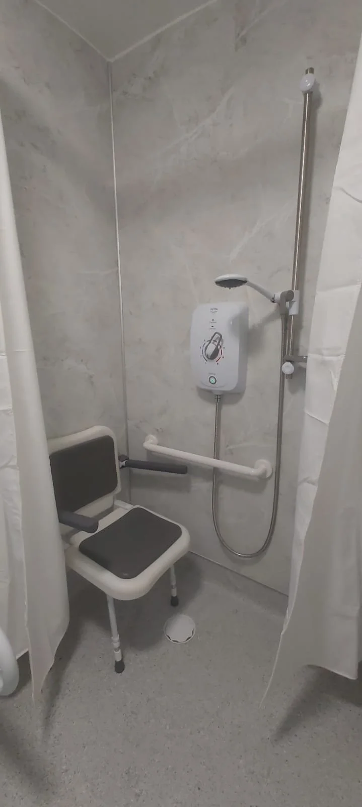 A clean, modern bathroom with a wall-mounted sink, a glass shower enclosure, a heated towel rail, and a toilet.