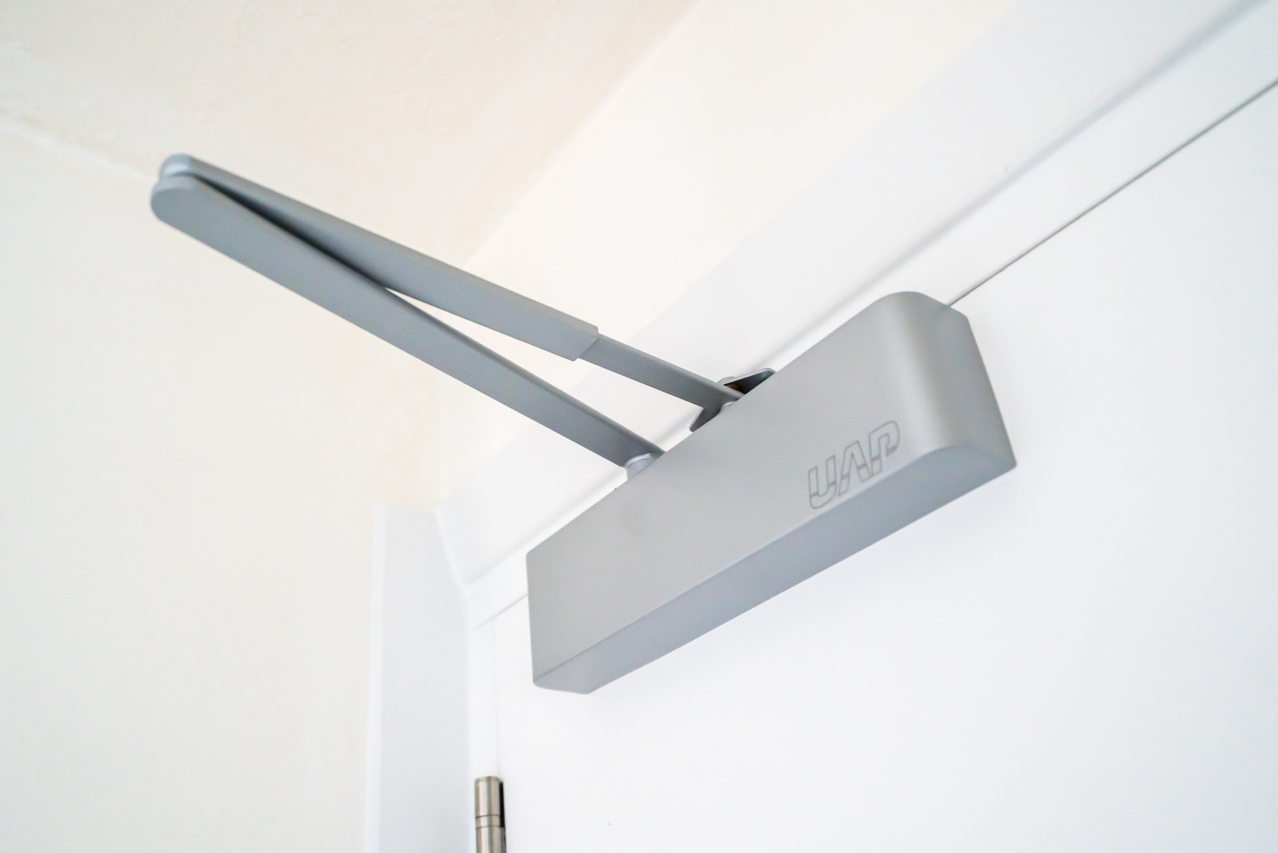 A white door with a metallic hinge and a mounted device labeled 'UAP' with two extending antennas.
