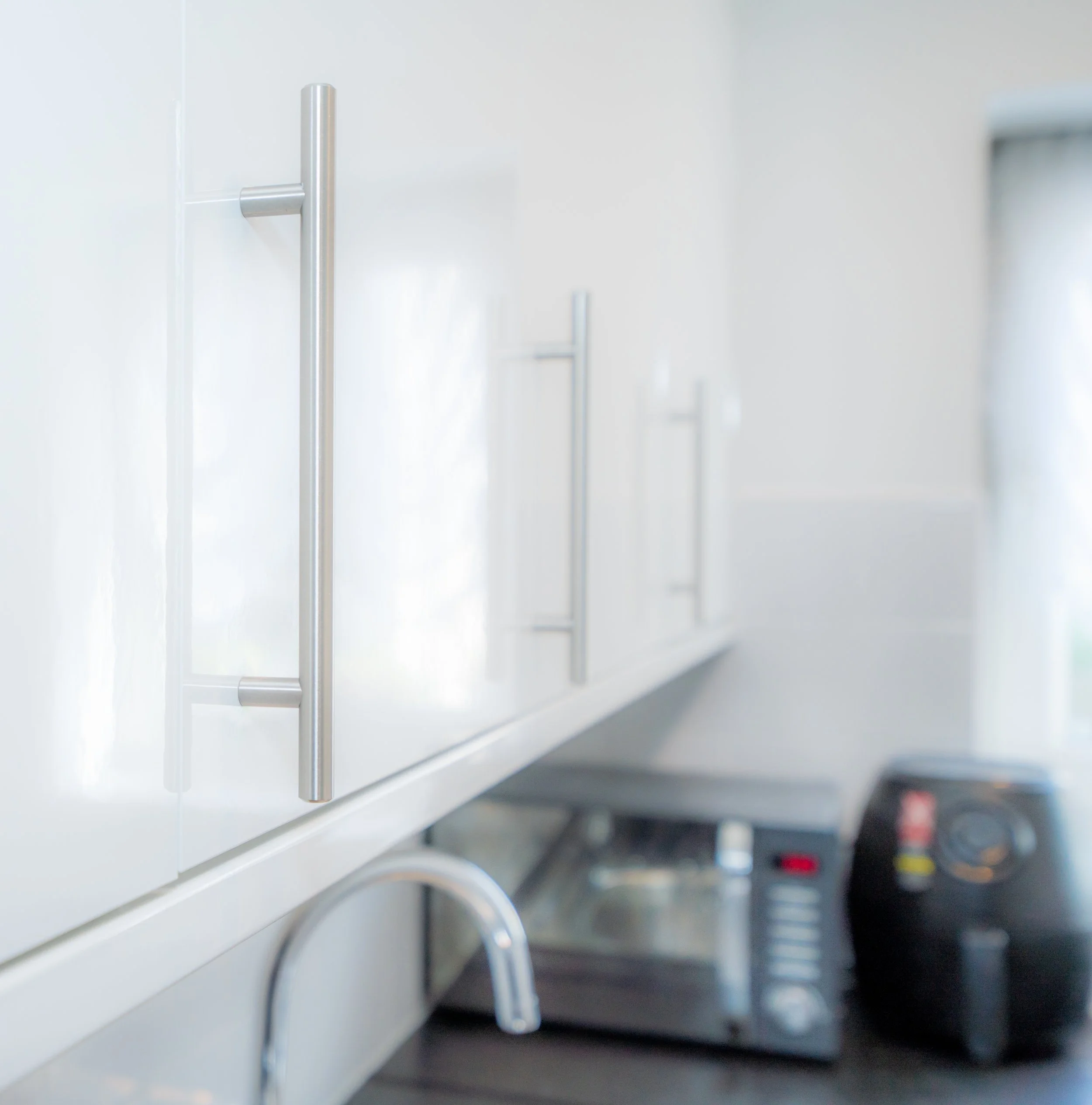 Close-up view of a white microwave oven with a stainless steel handle on the door and modern design, placed on a dark kitchen countertop.
