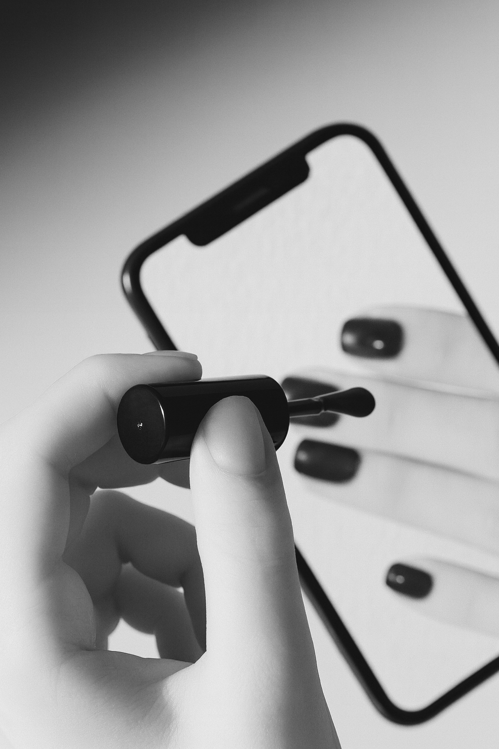 Close-up of a hand holding applying nail polish through a smartphone