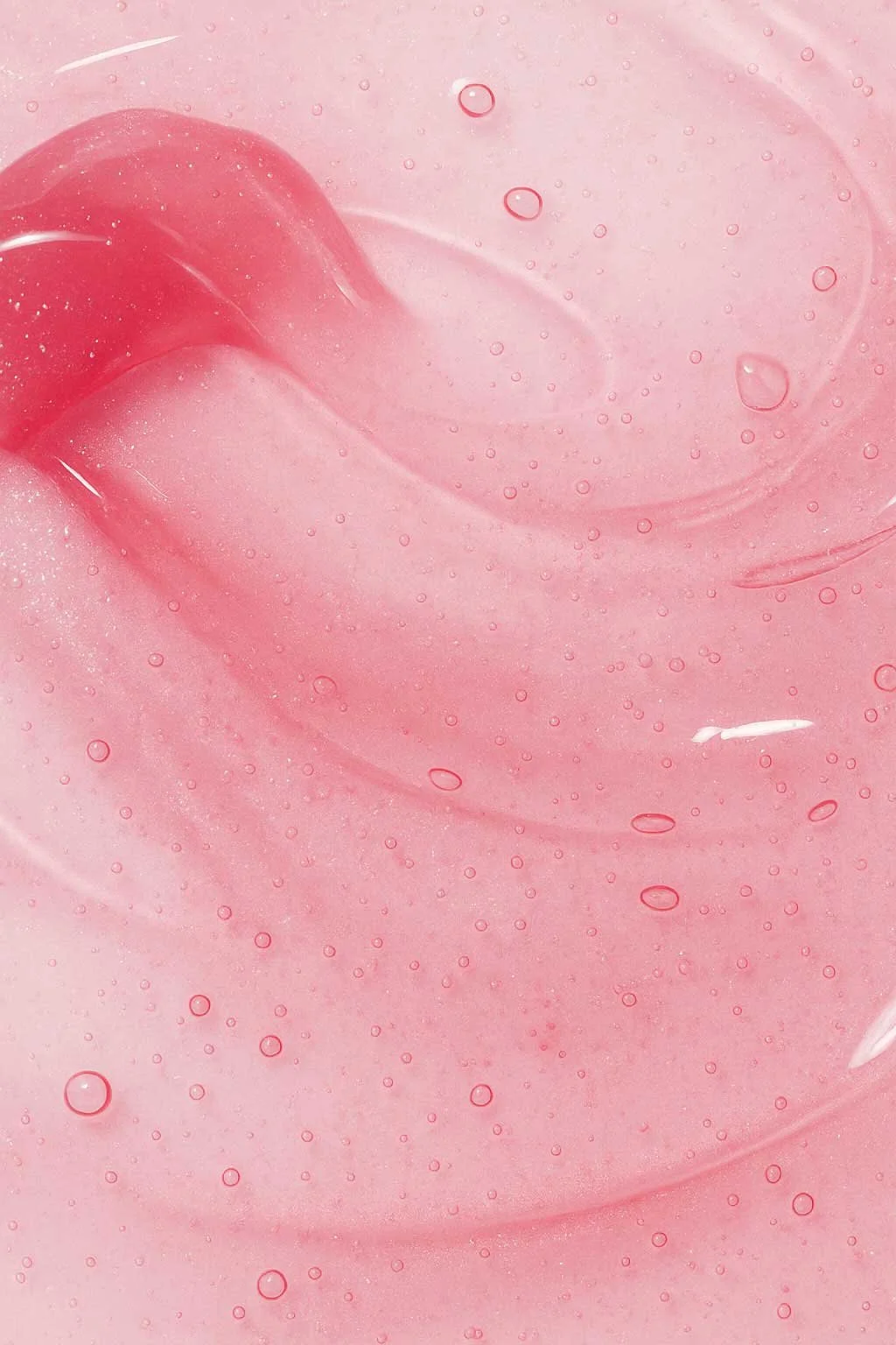 Close-up of a pink, gel-like substance with small bubbles and a smooth texture.