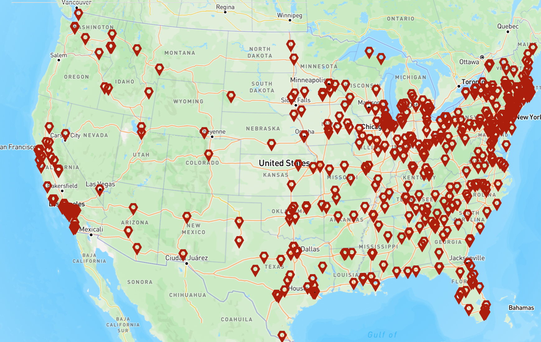 Two college students walking outside on campus, smiling, holding notebooks and a phone.