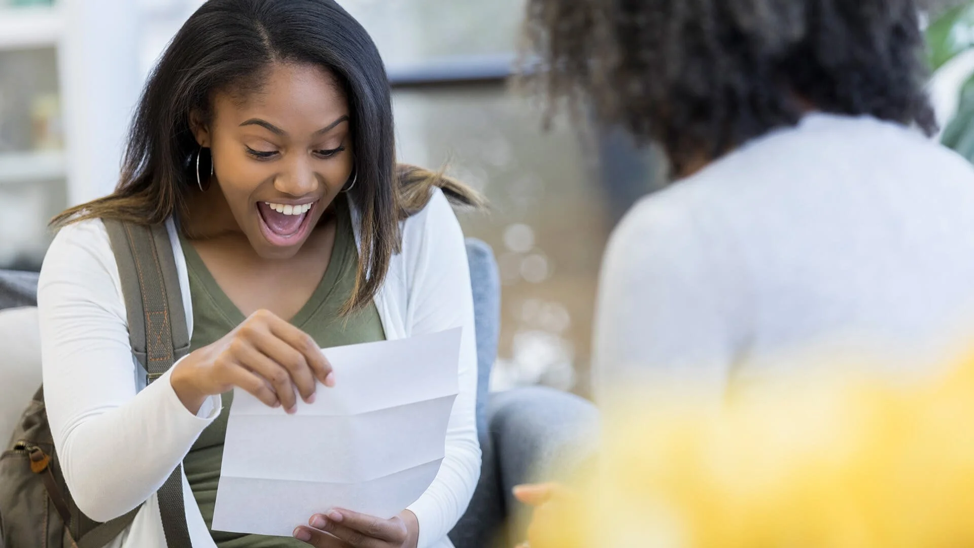 Two young women are looking at a map and smiling while sightseeing outdoors in front of a historic building.