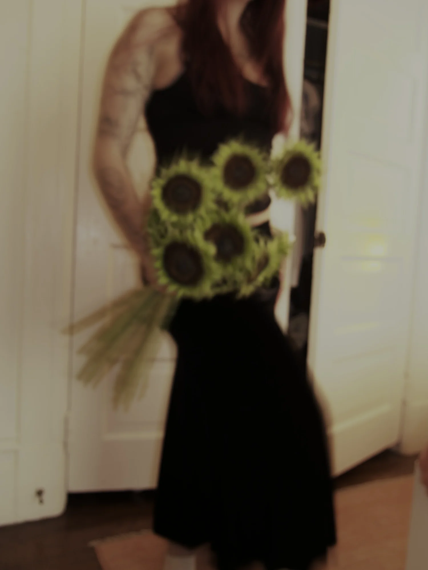 Haley holding sunflowers in a dim hallway