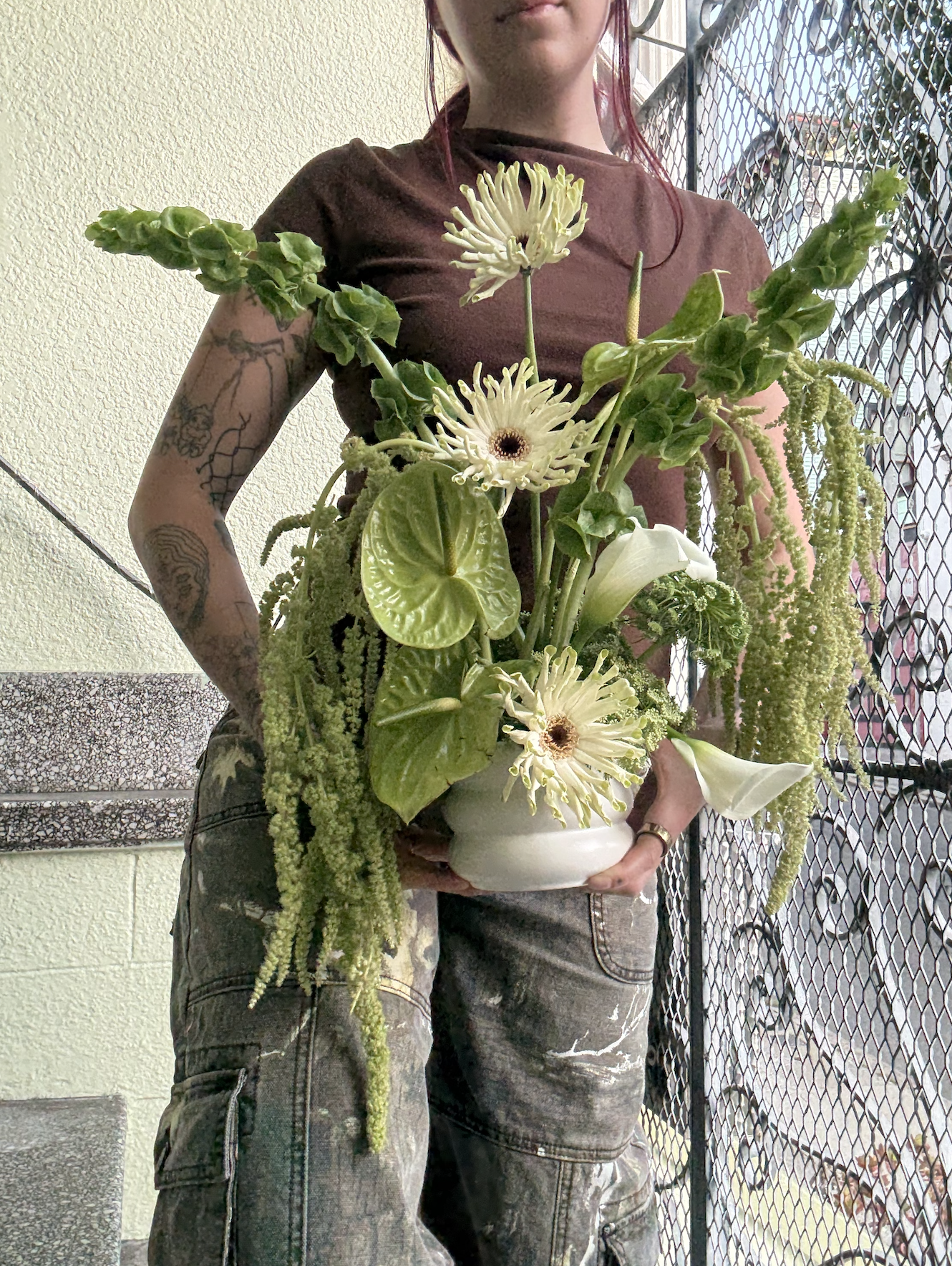 Haley holding a green anthurium and amaranthus arrangement