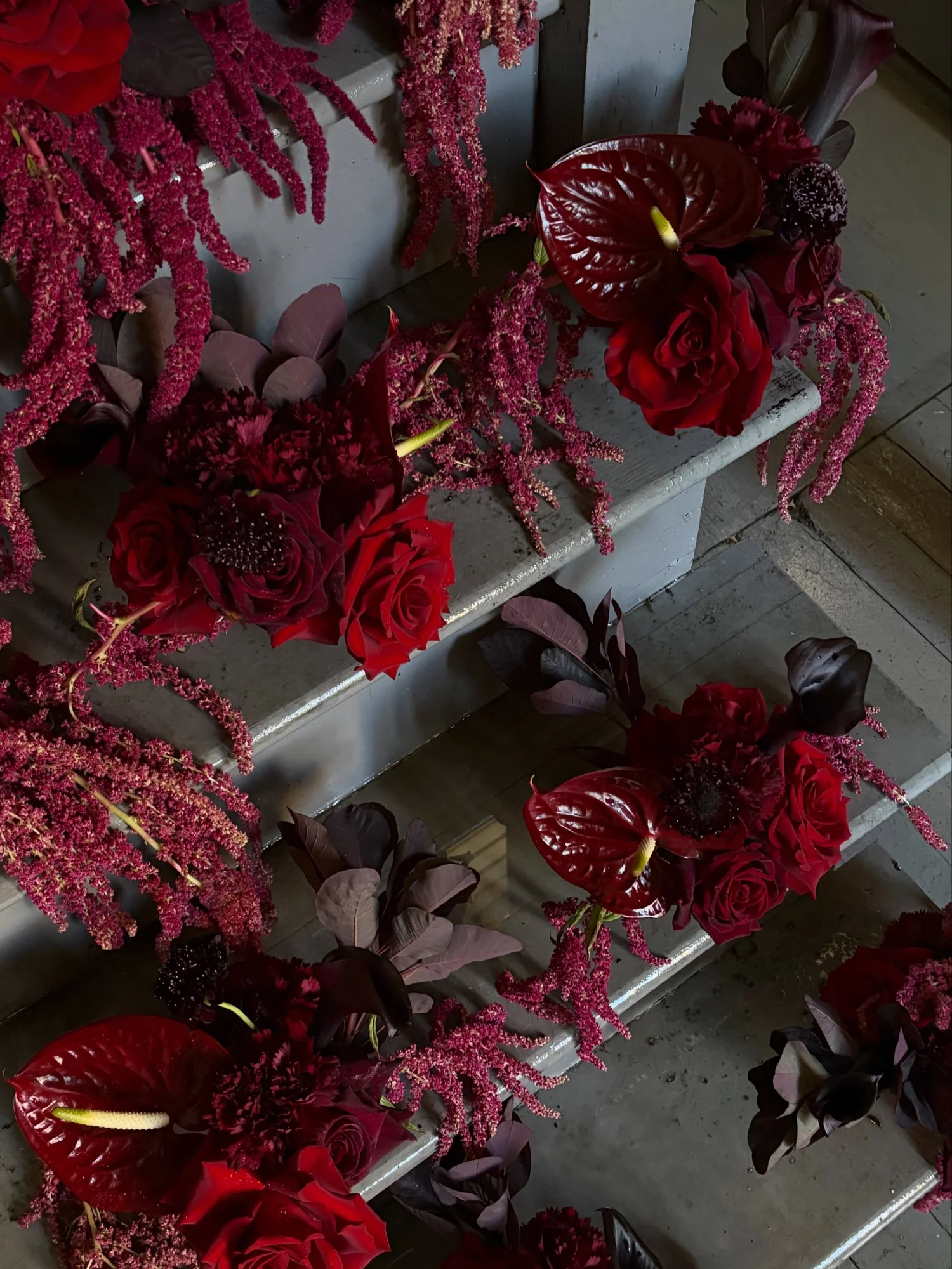Burgundy amaranth, anthurium and roses lining a stairway