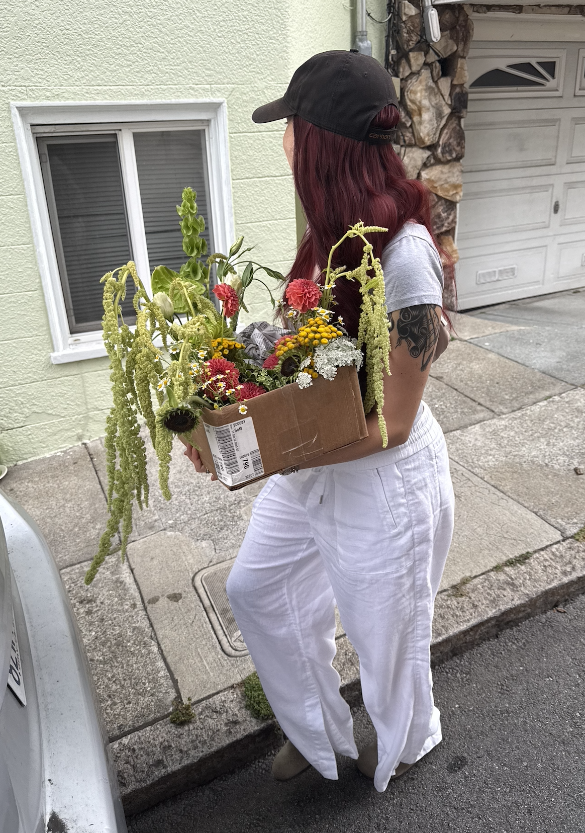 Haley carrying a box of amaranthus, dahlias and yarrow down a San Francisco street