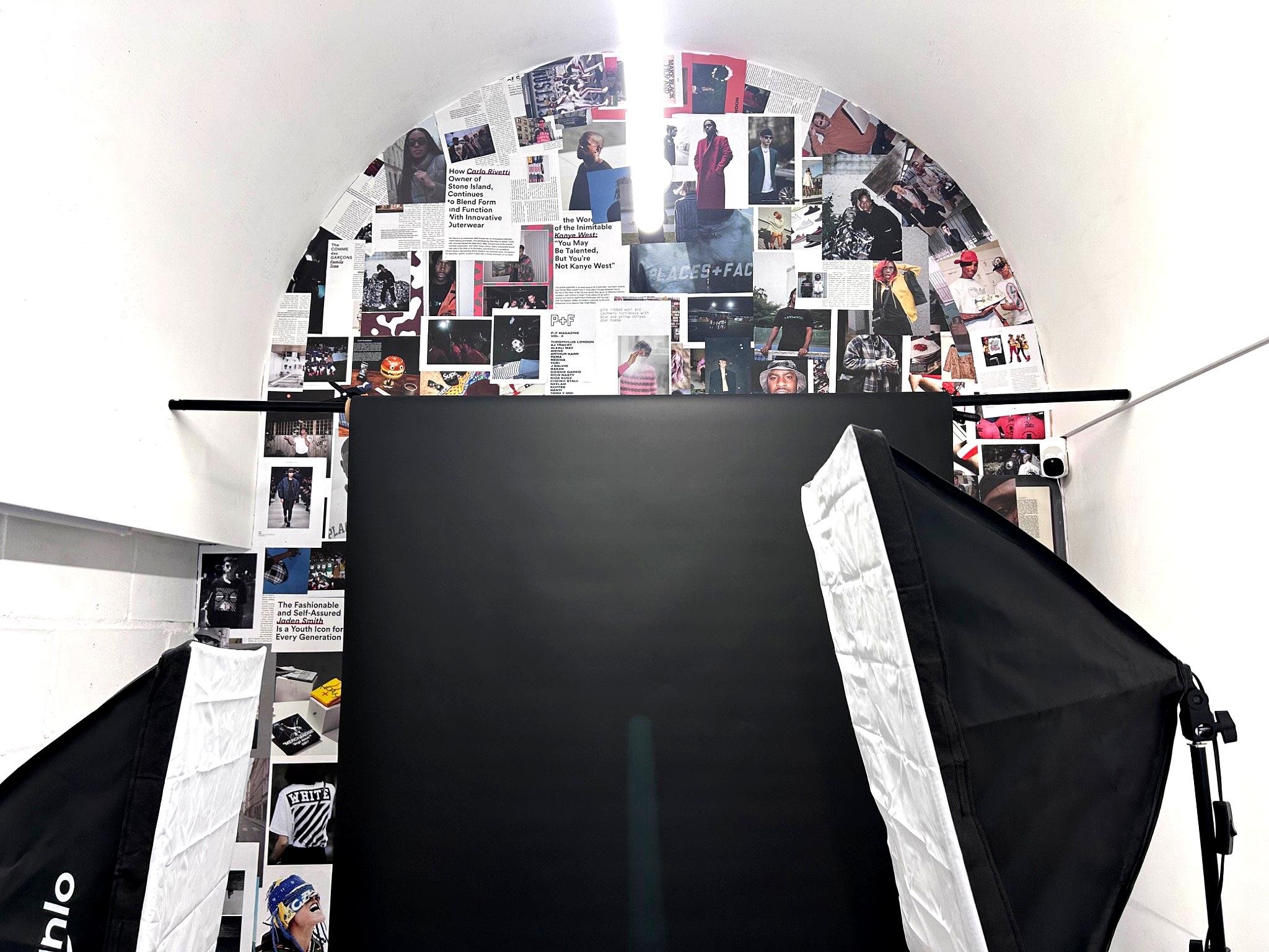 A white curved wall decorated with various magazine pages and photos of people, arranged in a collage style.