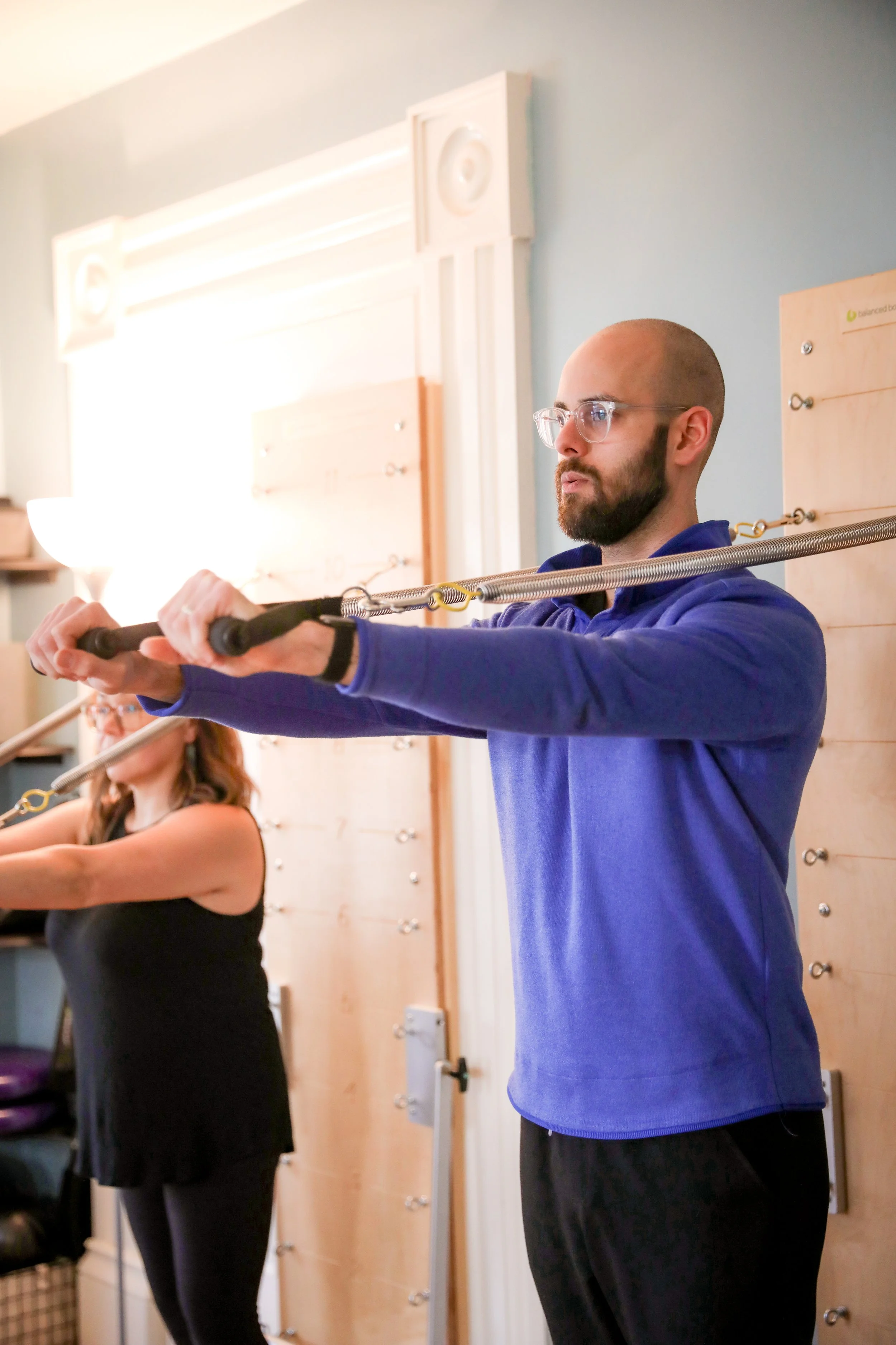 Man and woman using resistance bands during a workout in a fitness studio.