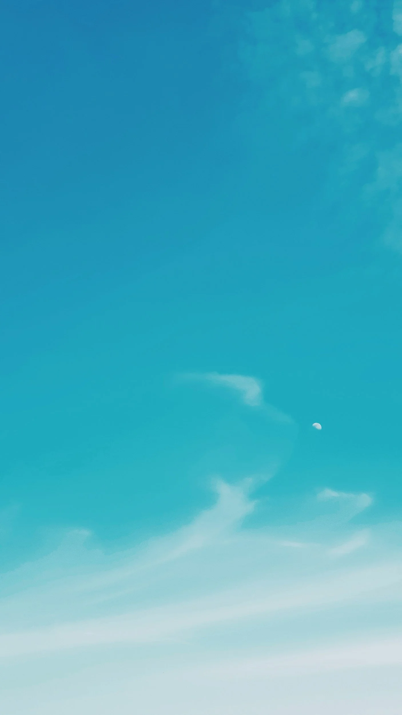 Clear blue sky with wispy white clouds and visible moon.