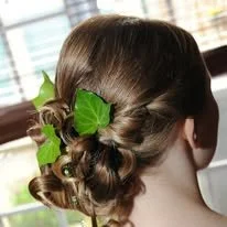 Coiffure d'une femme avec un chignon orné de feuilles vertes décoratives.