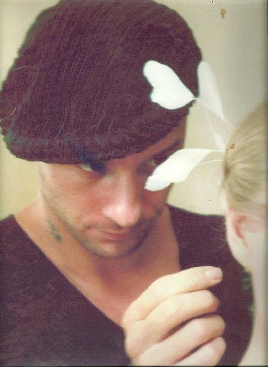 Un jeune homme regarde une jeune fille dont la tête est coupée sur la droite de l'image. Il y a un papillon blanc posé sur la tête de la fille.