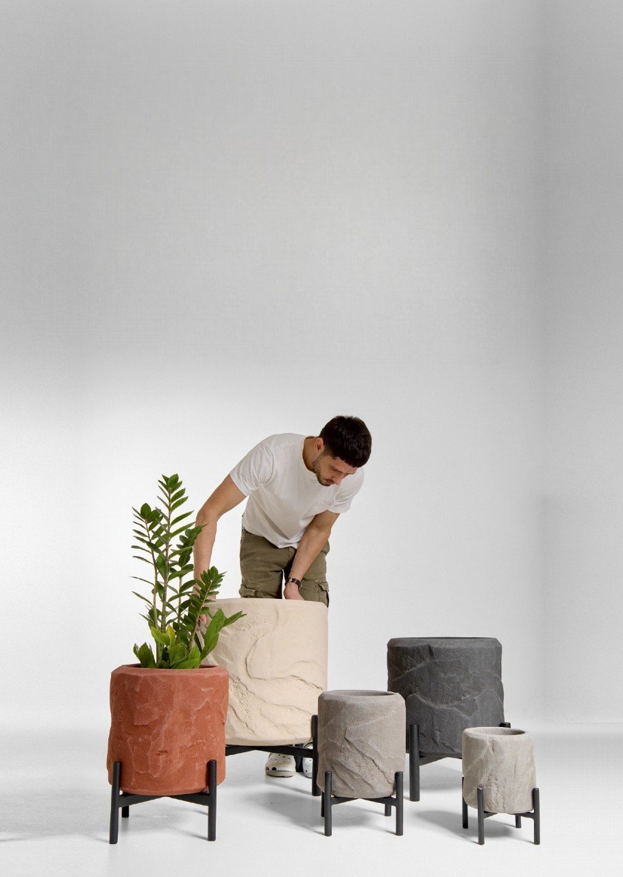 Arrangement of various white and cream-colored textured fabrics, yarns, and decorative objects on a white surface, including knitted swatches, plush textiles, a rolled shell-like object, and natural fiber pieces.