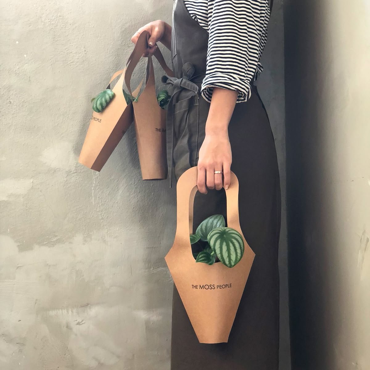 Stacked folded patterned blankets leaning against a white wall, with a wooden stool holding more folded blankets beside them.