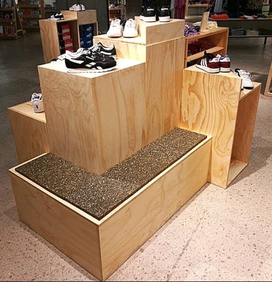 Wooden display stands with sneakers and shoes inside a retail store.