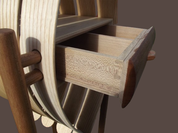 Close-up of a wooden drawer pulled out from a wooden chair.