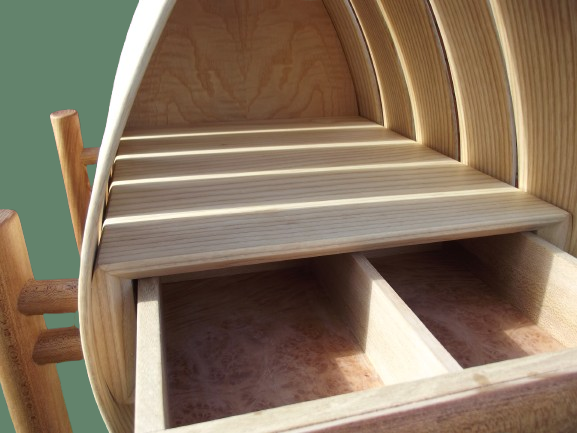 A wooden organizer or shelf with multiple curved slots, featuring a green background and part of a chair visible on the side.