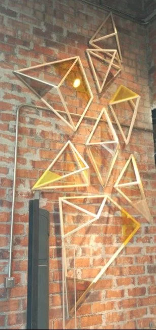 Decorative wall art made of wooden geometric shapes on a brick wall.